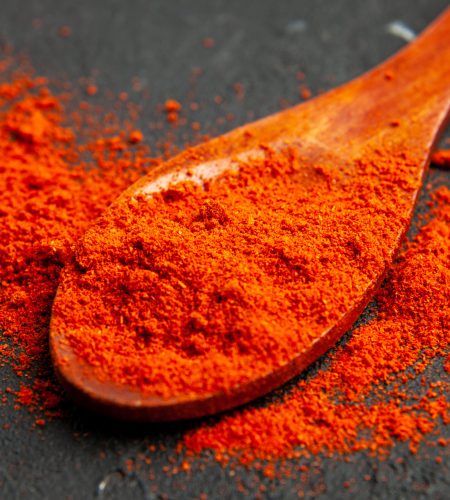bottom-view-red-pepper-powder-wooden-spoon-dark-surface